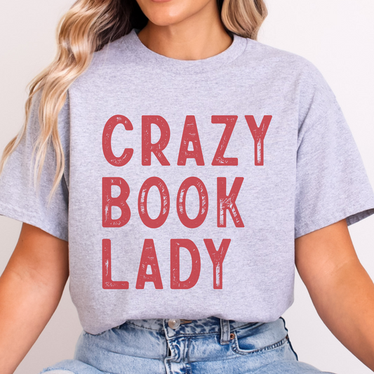 Person wearing a gray t-shirt with 'Crazy Book Lady' in red text on a plain background