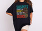 Suspect Claims to be busy but always has time for books Black oversized T-shirt,retro multi color text with an illustration of a stack of books